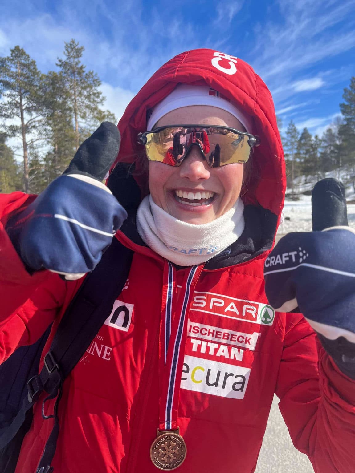 Hedda Bakkemo med medalje og tommel opp  – et bilde på mestring, idrettsglede og vinterfeiring.